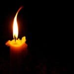A black background and a single orange candle and flame burn
