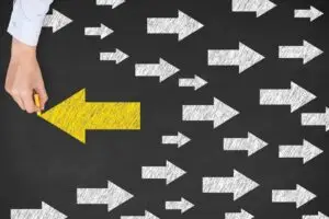 One yellow arrow pointing left and lost of white arrows pointing right. to show a change