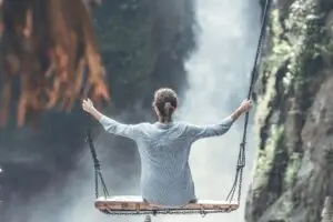 Woman sitting on a rope swing overlooking a massive water fall